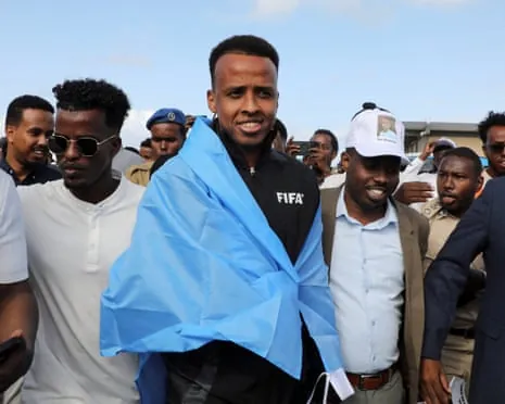 Omar Artan draped in a flag and surrounded by people at Mogadishu airport
